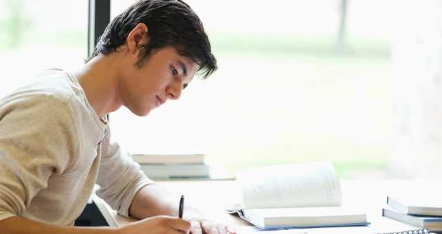 Serious male student writing in a laboratory