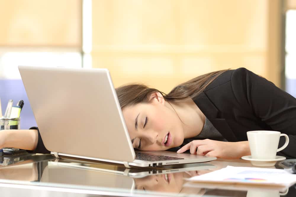 Overworked and tired businesswoman sleeping over a laptop in a desk at work in her office