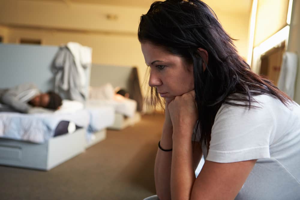 Women Sitting On Beds In Homeless Shelte